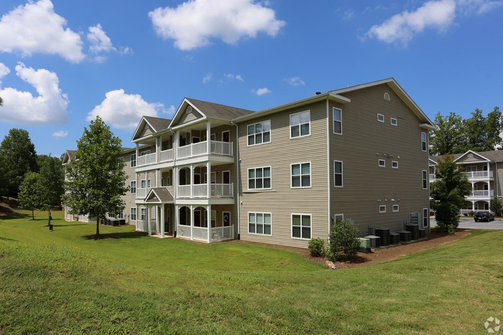 Building exteriors with mature landscaping at The Columns at Oakwood, GA 30566