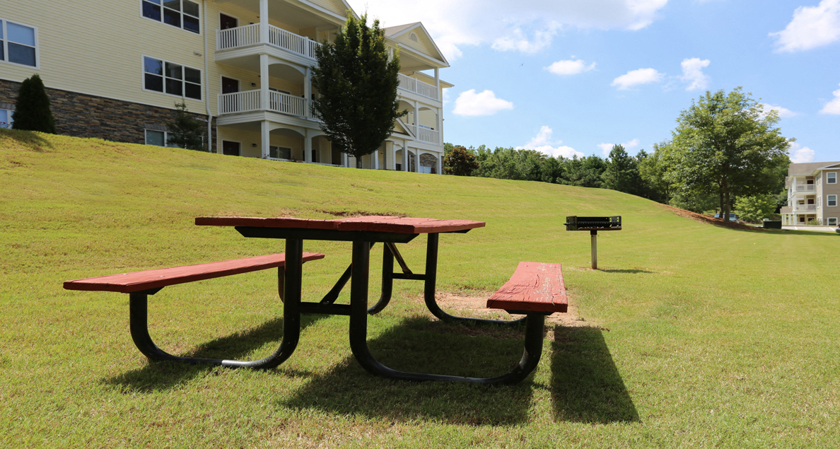Community picnic area with table and charcoal grill at The Columns at Oakwood, Oakwood, GA