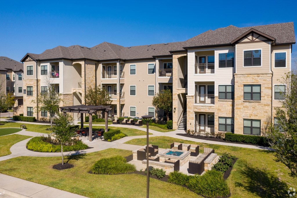 Outdoor destination courtyard with gas grills and a fire pit at The Columns at Shadow Creek Ranch, Pearland, Texas