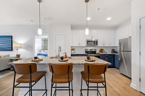 an open kitchen with a marble counter top with four stools