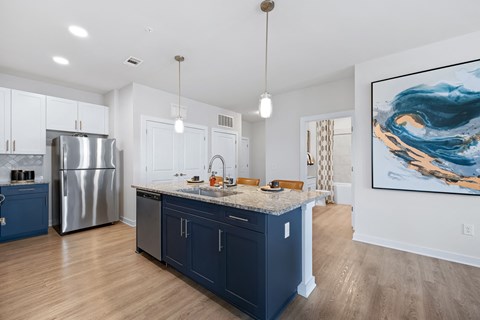 a large kitchen with a blue island and stainless steel refrigerator