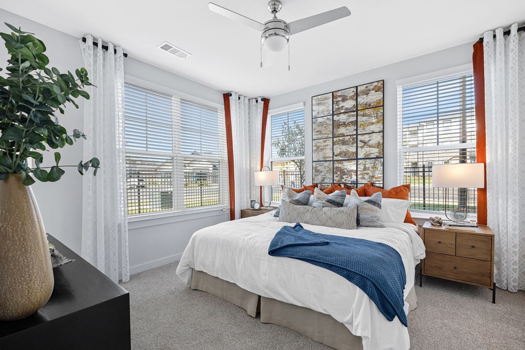 a bedroom with a large bed and three windows