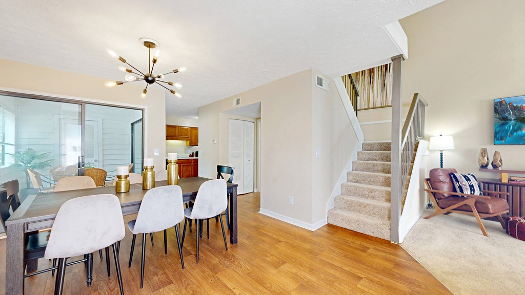 a dining area with a table and chairs and a staircase in the background