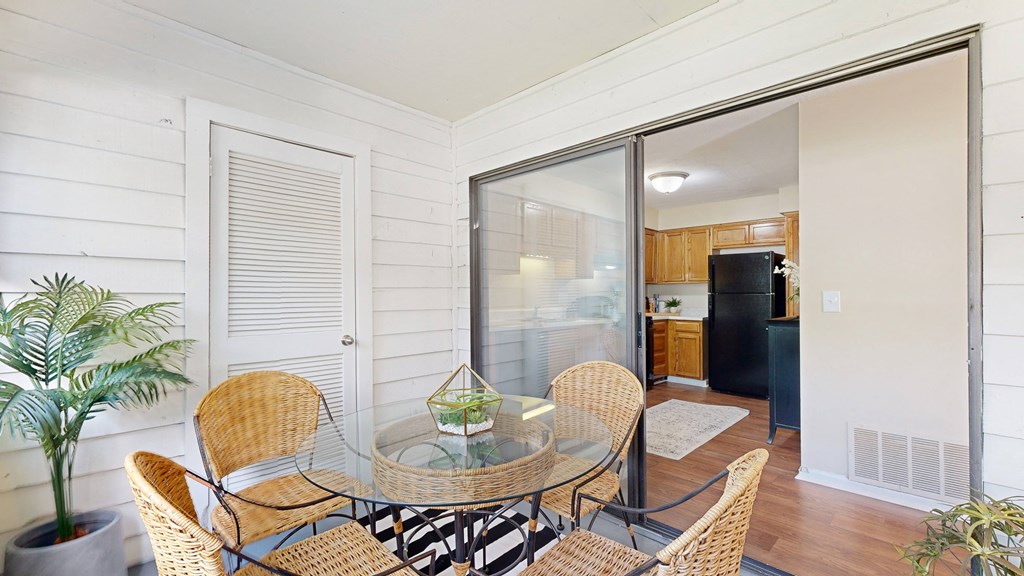 a small dining area with a glass table and rattan chairs