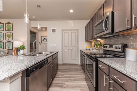 A modern kitchen with dark brown cabinets and stainless steel appliances.