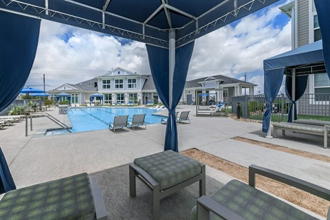 A pool area with a blue canopy and a building in the background.