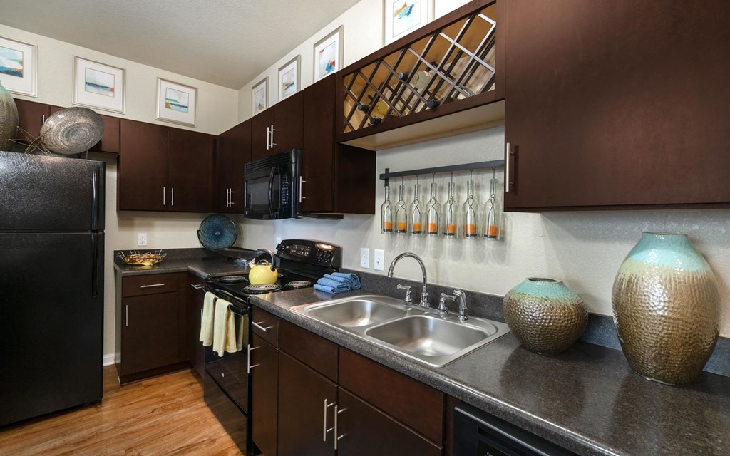 a kitchen with dark cabinets and a stainless steel sink