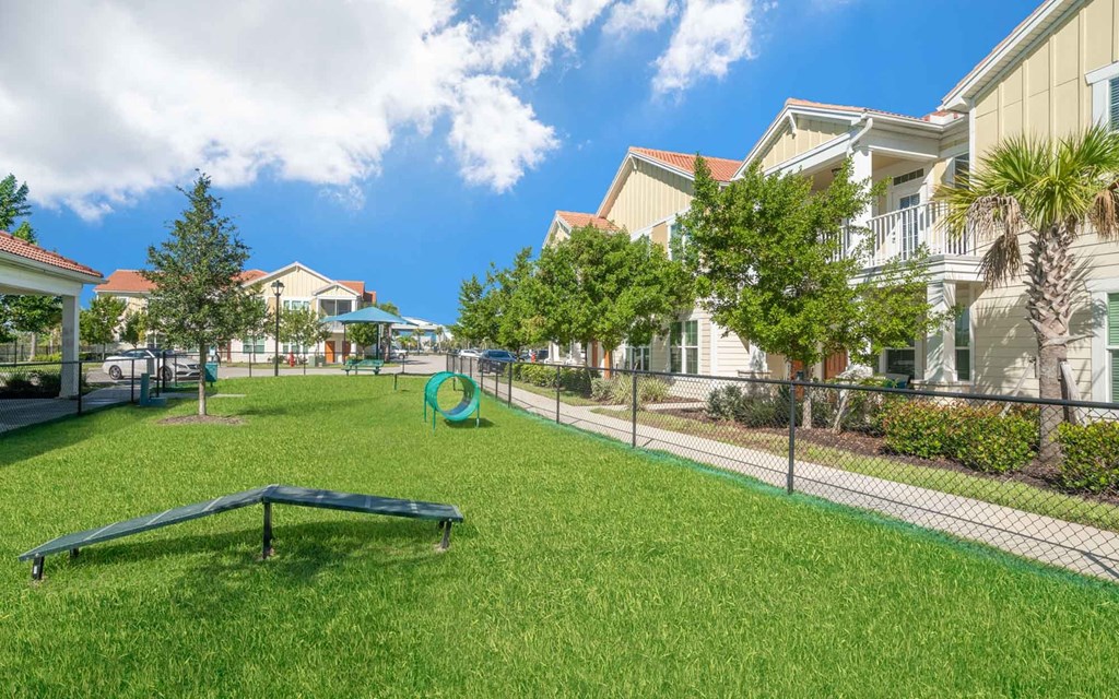 a grassy area with a trampoline in front of a row of houses