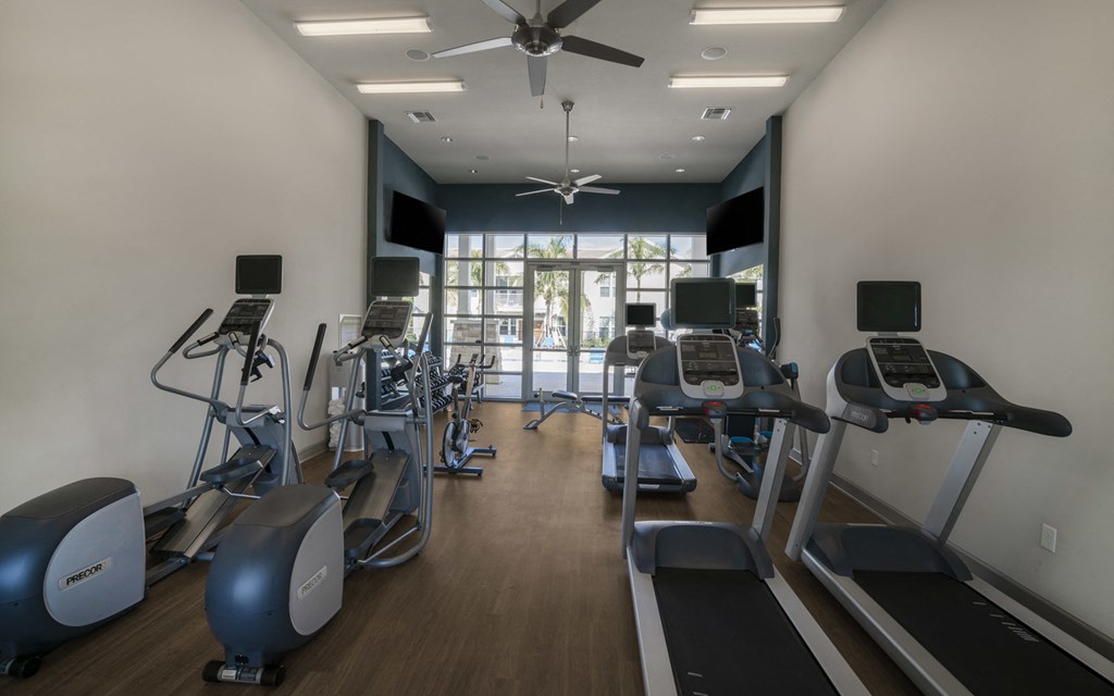 a room filled with cardio equipment and a ceiling fan