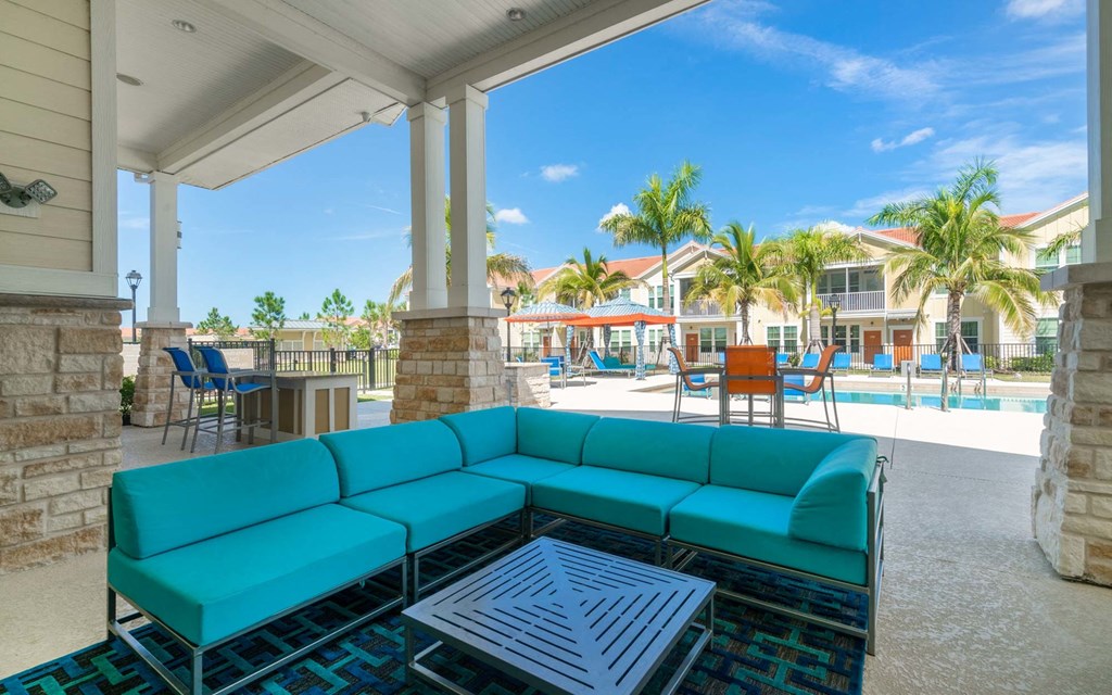 a covered patio with a turquoise couch and a coffee table