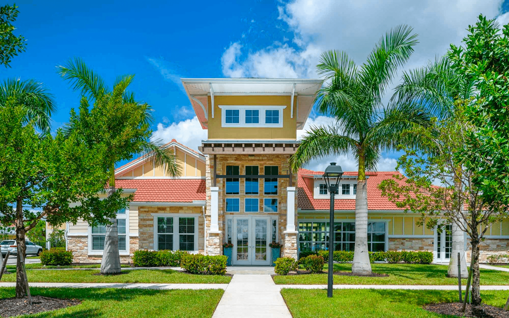a large yellow house with palm trees in front of it
