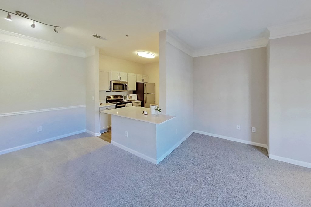 an empty living room and kitchen with white walls and carpet
