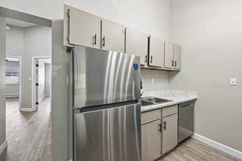 A kitchen with a stainless steel refrigerator and white cabinets.