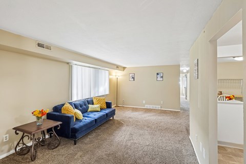 A living room with a blue couch and a table with a vase of flowers on it.