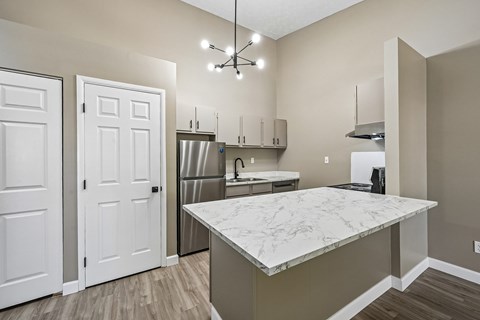 A kitchen with a marble countertop and white doors.