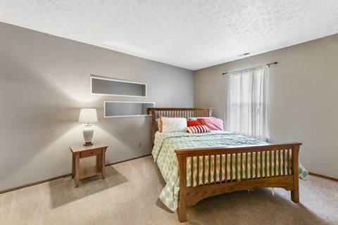 A bedroom with a bed, nightstand, and lamp.