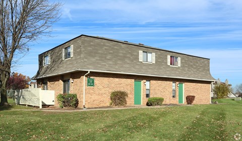 A small brick building with a green door and a sign on the front.