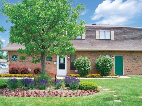 A house with a green door and a tree in front.