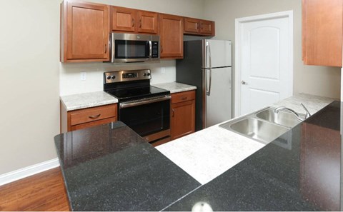 A kitchen with a black counter top and wooden cabinets.