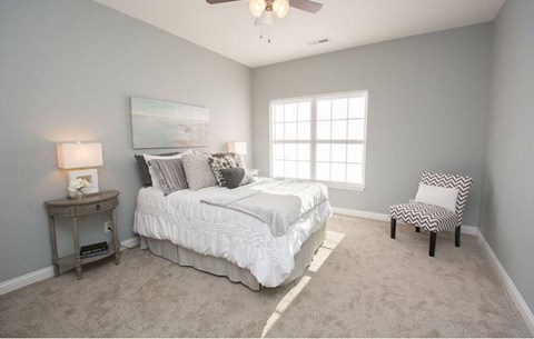 A bedroom with a bed, chair, and a painting on the wall.