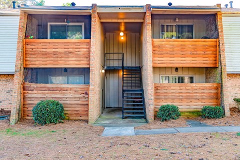 A two-story wooden house with a black staircase leading to the entrance.