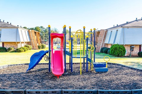 A playground with a red slide and a blue slide.