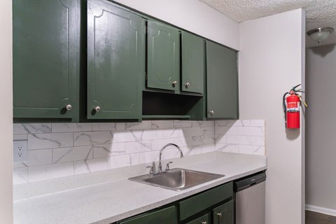 A kitchen with green cabinets and a white counter top.