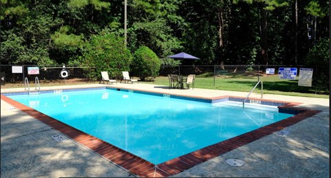 A rectangular pool with a red border and a blue umbrella.