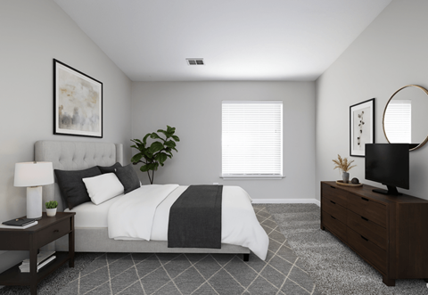 A bedroom with a bed, nightstand, and a plant.