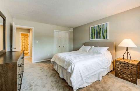 A bedroom with a large bed and a wooden nightstand.