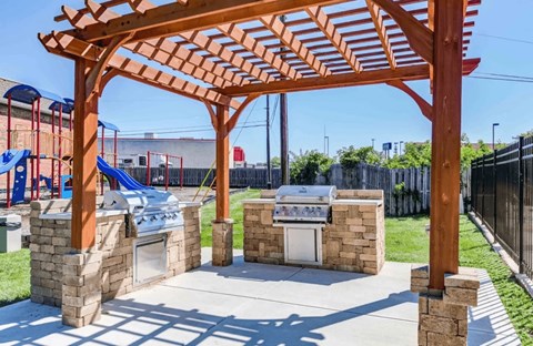 A playground with a wooden pergola and a slide in the background.