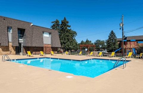 A large swimming pool with yellow chairs around it.