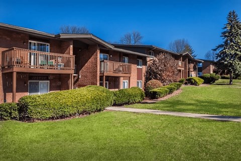 Apartment complex with green lawn and trees.