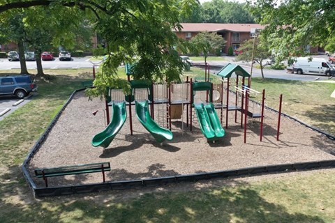 A playground with a green slide and a red and green play structure.