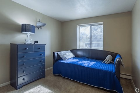 A bedroom with a blue bed and a dresser.