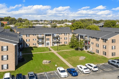 A sunny day at a residential complex with cars parked in the lot.