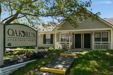 A sign that says Oak Run Apartment Homes in front of a house.