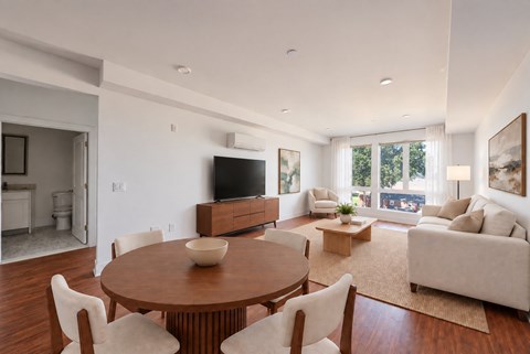 A modern living room with a wooden table and white chairs.
