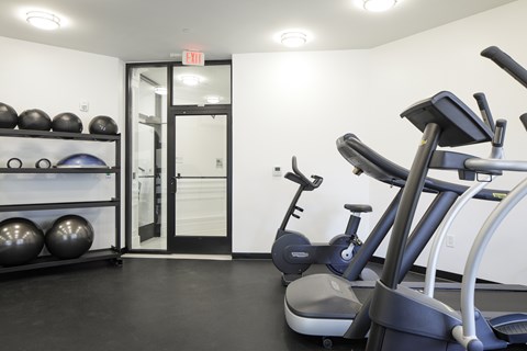 A gym with a treadmill, exercise balls, and weights.