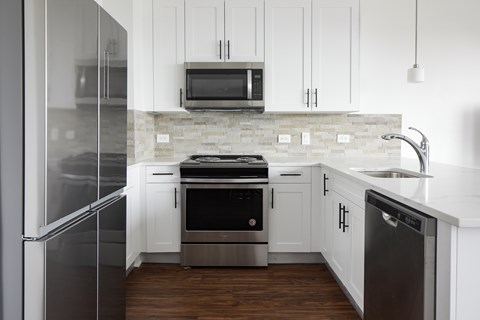 A modern kitchen with white cabinets and stainless steel appliances.