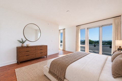 A bedroom with a large bed and a dresser with a mirror above it.