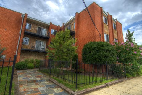 A brick building with a black fence and a stone pathway leading to the entrance.