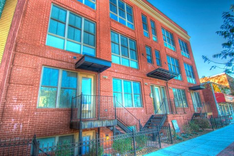 A red brick building with a balcony and a black railing.