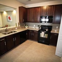 A kitchen with dark wood cabinets and a black stove top oven.