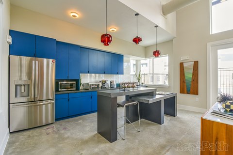 A kitchen with blue cabinets and a stainless steel refrigerator.