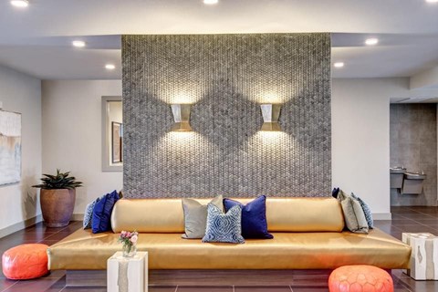 A modern living room with a gold sofa and a grey textured wall.