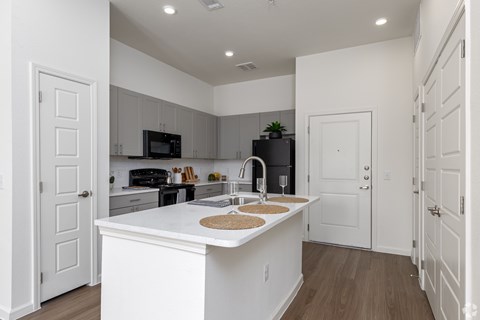 A kitchen with white cabinets and a white island with a sink.