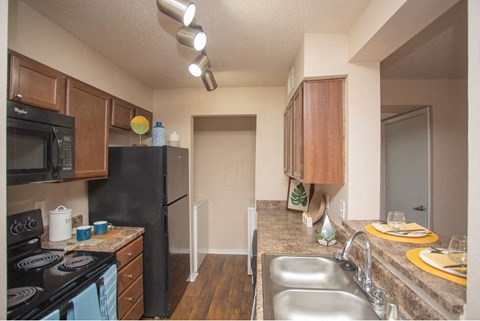 A kitchen with a black refrigerator and a blue stove.