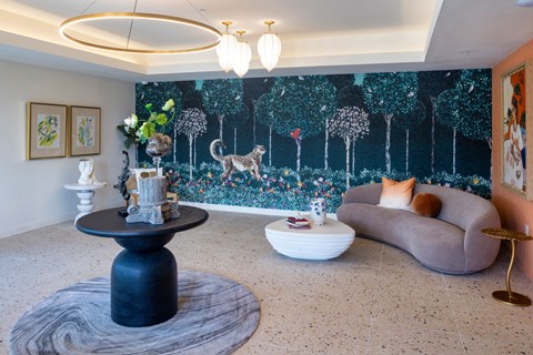 A living room with a grey couch, a black table and a wall mural.