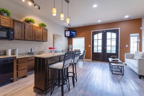 A kitchen with wooden cabinets and a bar area with stools.